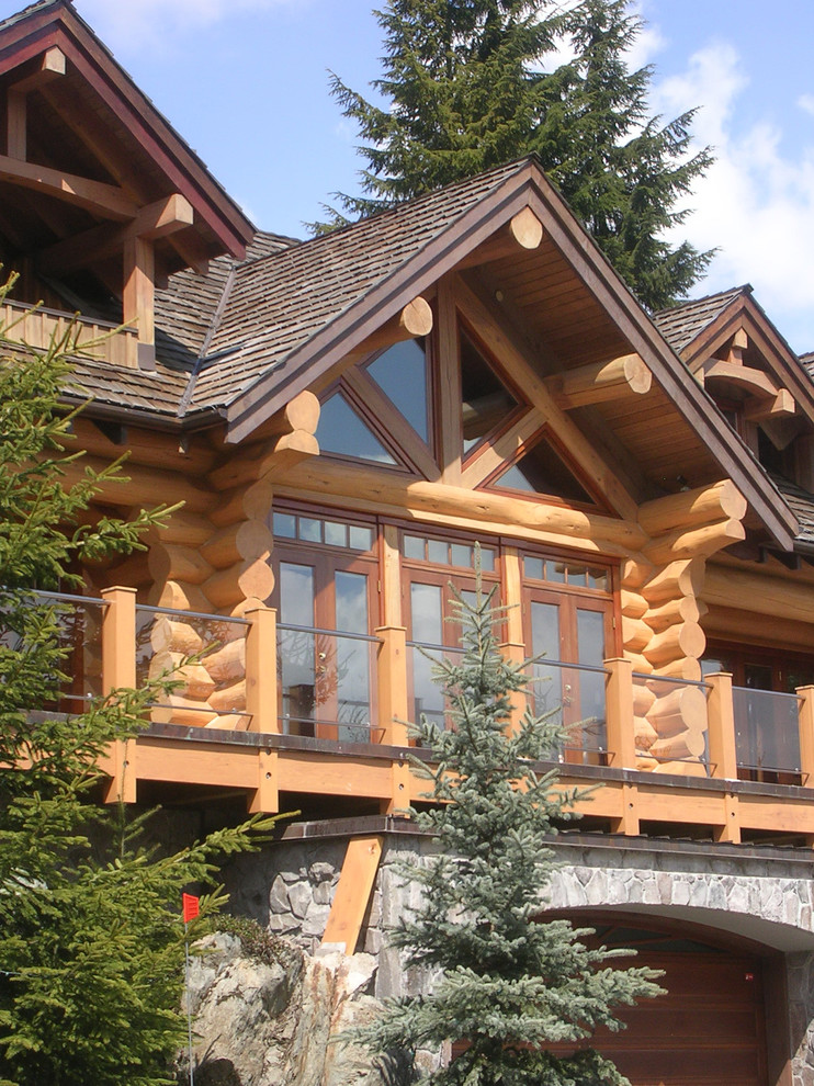 Diseño de fachada de casa marrón rústica grande de tres plantas con revestimiento de piedra y tejado a doble faldón