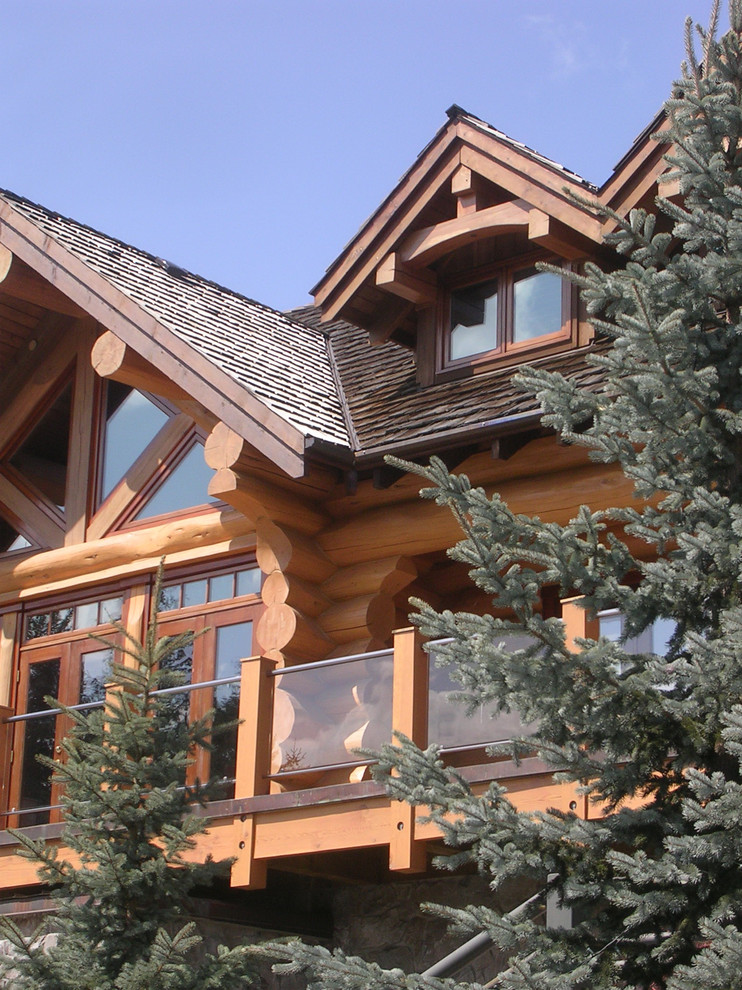 This is an example of a large and brown rustic detached house in Vancouver with three floors, stone cladding and a mansard roof.