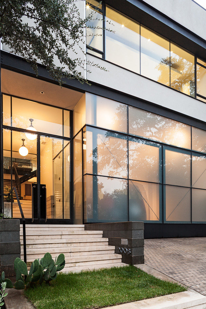 This is an example of a large and black contemporary two floor glass house exterior in Austin with a flat roof.