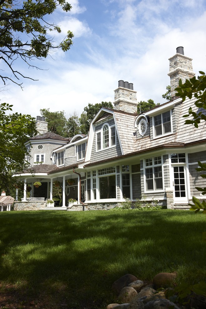 Esempio della villa grande grigia classica a due piani con rivestimento in legno, tetto a mansarda e copertura a scandole