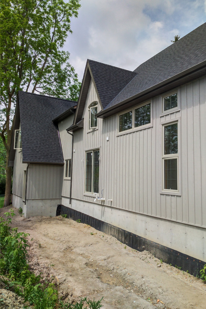 На фото: двухэтажный, деревянный, серый частный загородный дом в классическом стиле с крышей из гибкой черепицы