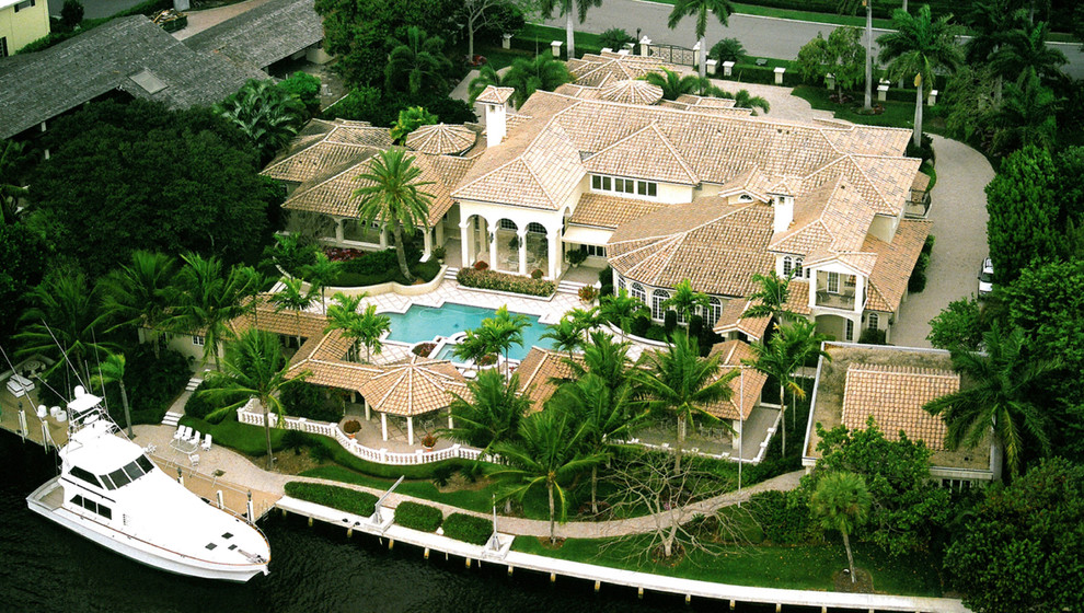 Пример оригинального дизайна: огромный, двухэтажный, белый частный загородный дом в средиземноморском стиле с облицовкой из цементной штукатурки, вальмовой крышей и черепичной крышей