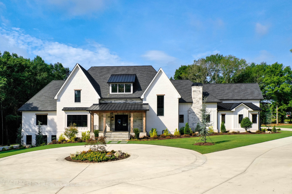Cette photo montre une grande façade de maison blanche moderne en briques peintes et planches et couvre-joints à deux étages et plus avec un toit mixte et un toit noir.