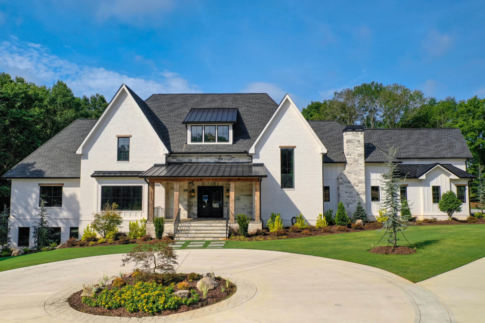 Immagine della villa grande bianca moderna a tre piani con rivestimento in mattone verniciato, copertura mista, tetto nero e pannelli e listelle di legno