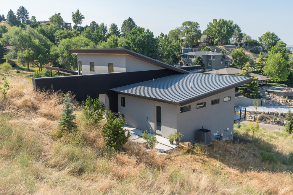 Mid-sized contemporary gray two-story stucco house exterior idea in Boise with a butterfly roof and a metal roof