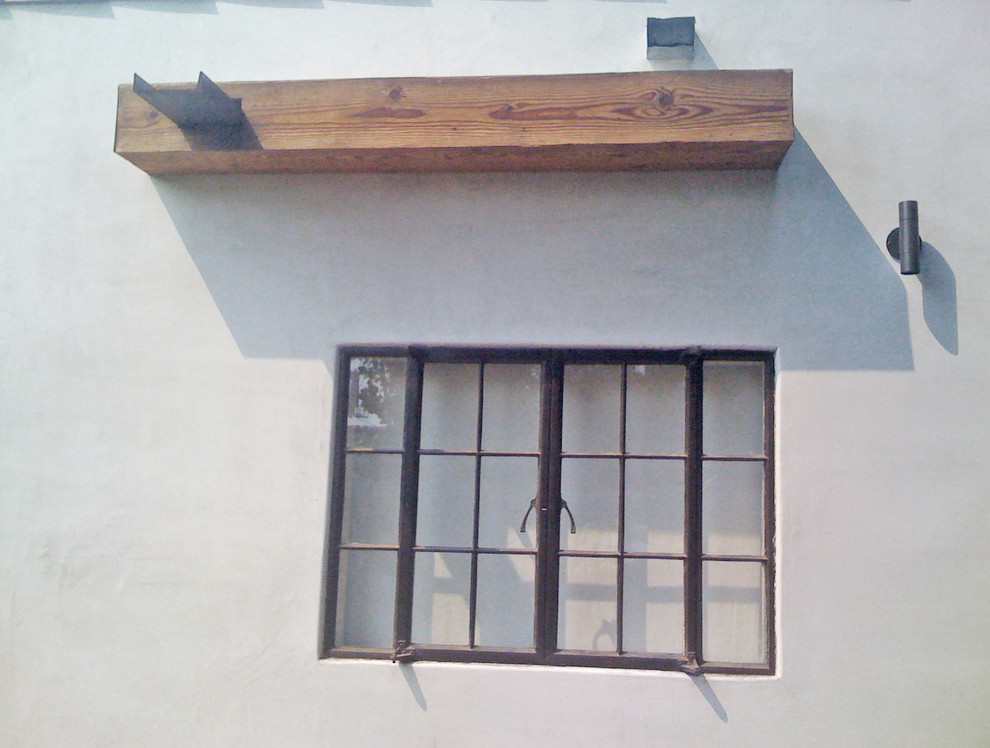 Réalisation d'une petite façade de maison blanche chalet en stuc de plain-pied avec un toit plat et un toit en shingle.