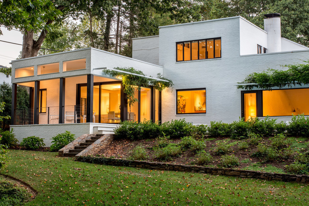 Idée de décoration pour une grande façade de maison blanche design en brique à un étage avec un toit plat.