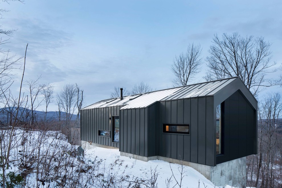 Modelo de fachada de casa gris moderna de tamaño medio de dos plantas con revestimiento de metal, tejado a dos aguas y tejado de metal