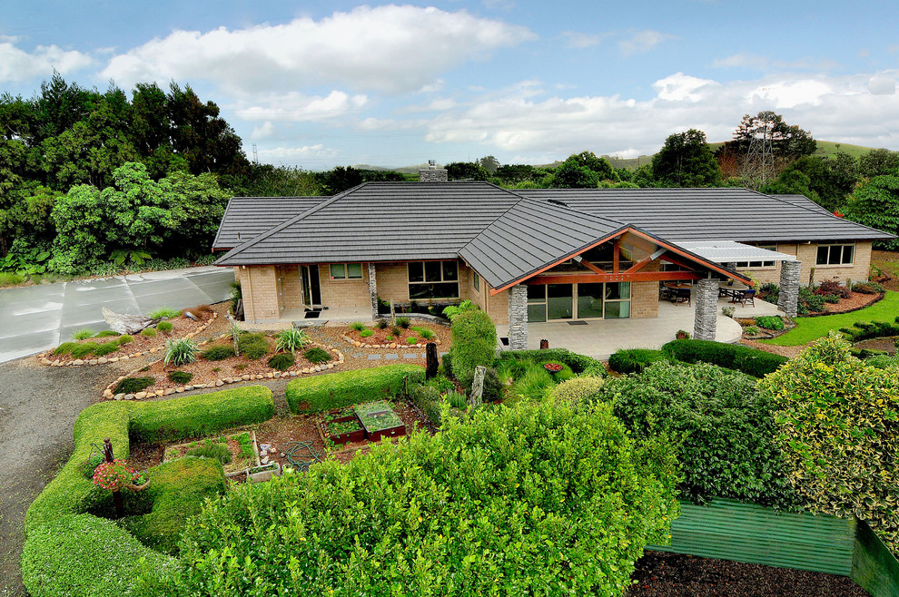 Photo of a large and beige classic bungalow brick house exterior in Auckland.