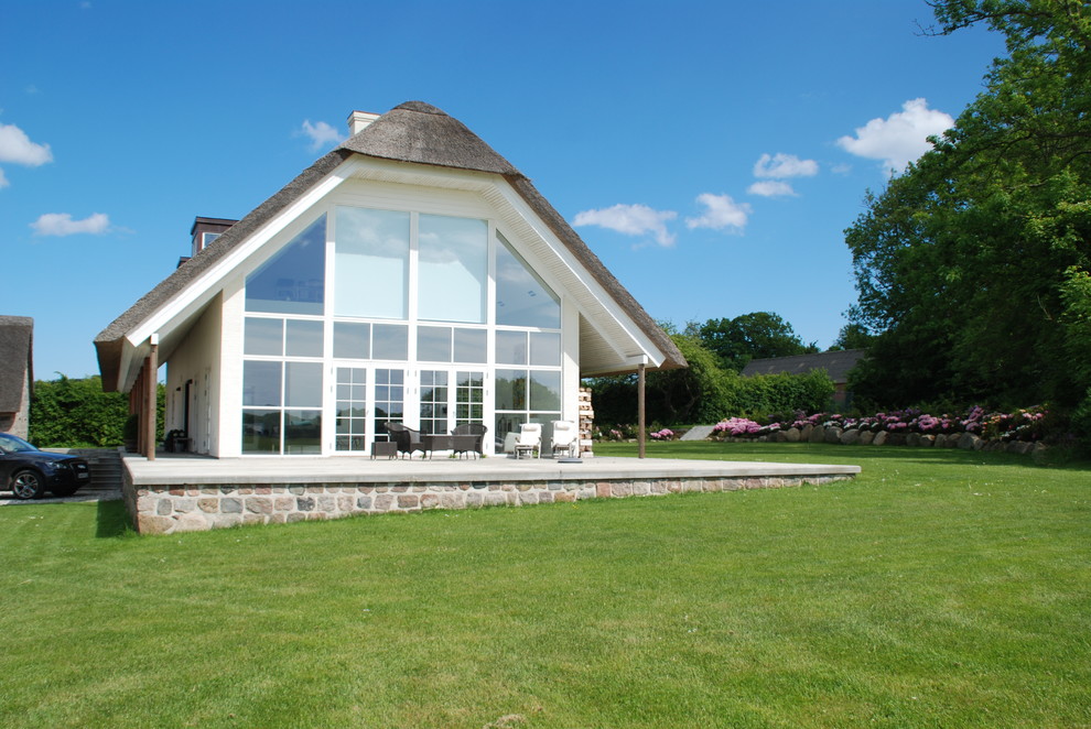 Cette photo montre une grande façade de maison blanche nature en verre avec un toit en appentis.