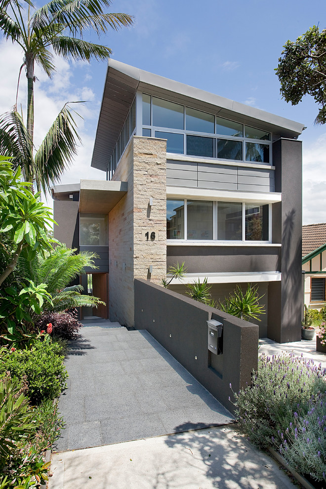 Photo of a large and brown modern detached house in Sydney with three floors, stone cladding, a flat roof and a metal roof.