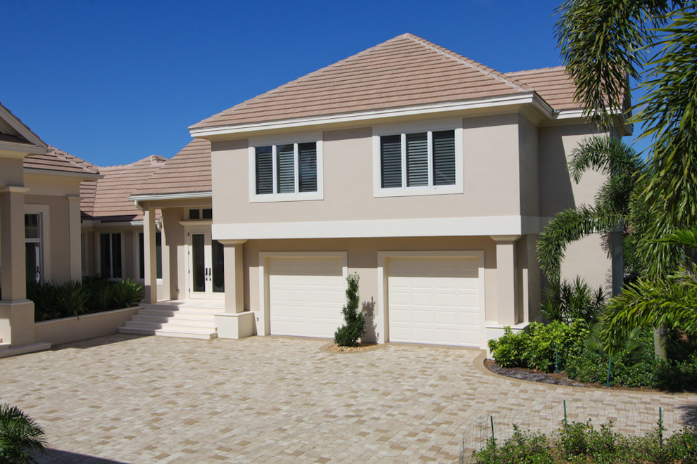 This is an example of a beige mediterranean two floor render detached house in Miami with a pitched roof and a tiled roof.