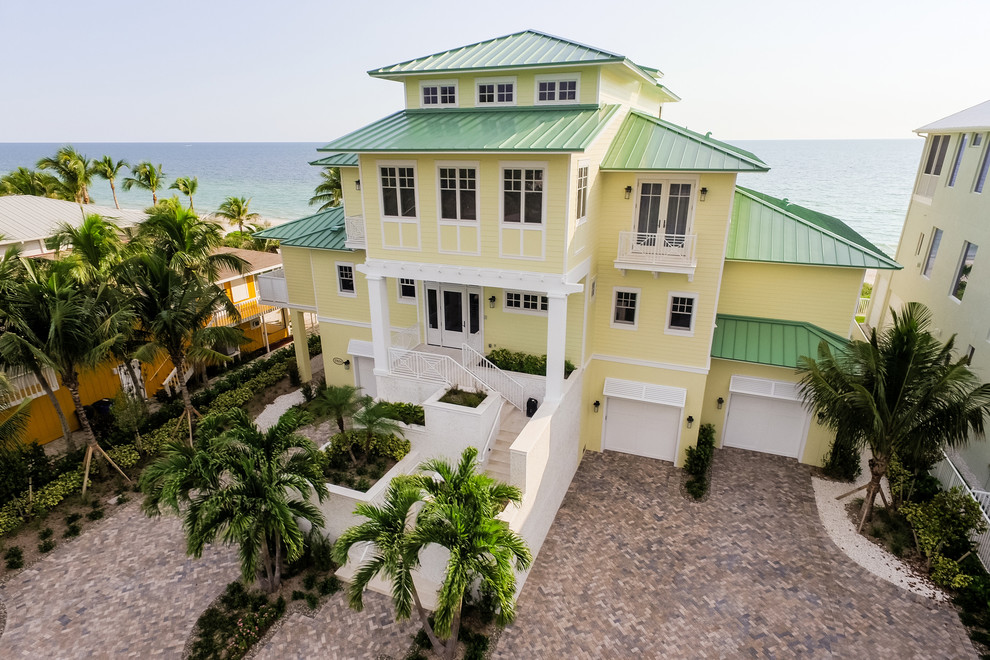 Cette image montre une grande façade de maison jaune marine à deux étages et plus avec un revêtement en vinyle et un toit à quatre pans.