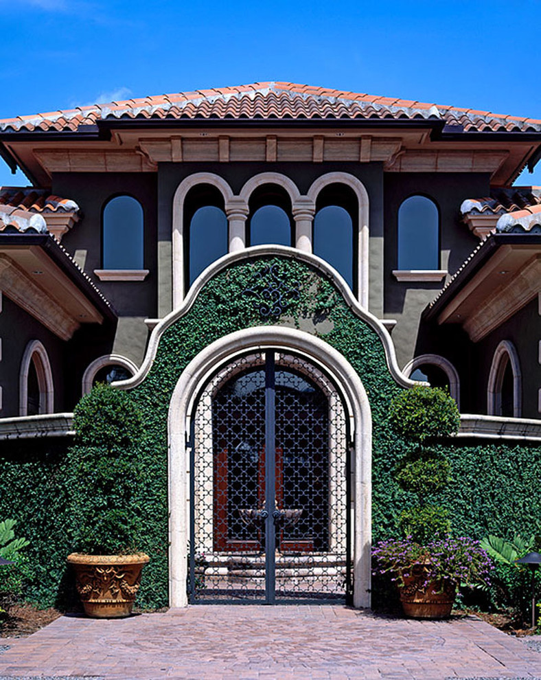 Diseño de fachada de casa verde mediterránea grande de dos plantas con revestimientos combinados, tejado a dos aguas y tejado de teja de barro