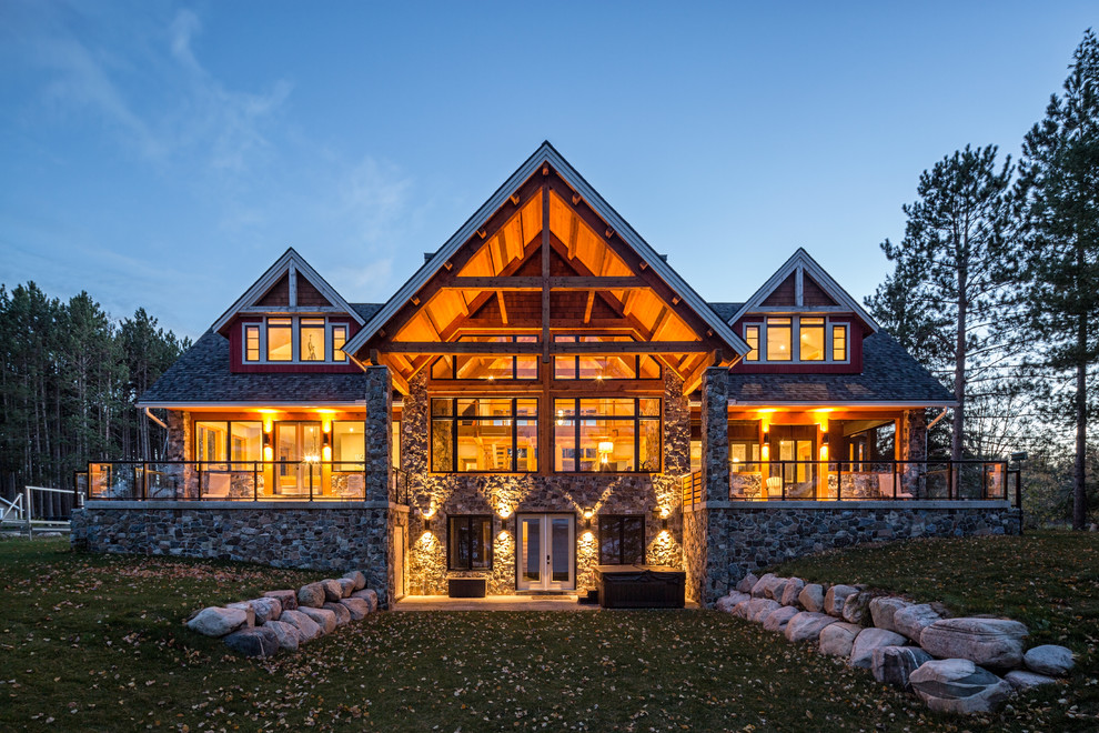 Cette image montre une très grande façade de maison rouge chalet en bois à un étage avec un toit à deux pans.