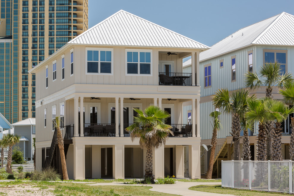 Diseño de fachada beige costera de tamaño medio de tres plantas con revestimiento de aglomerado de cemento