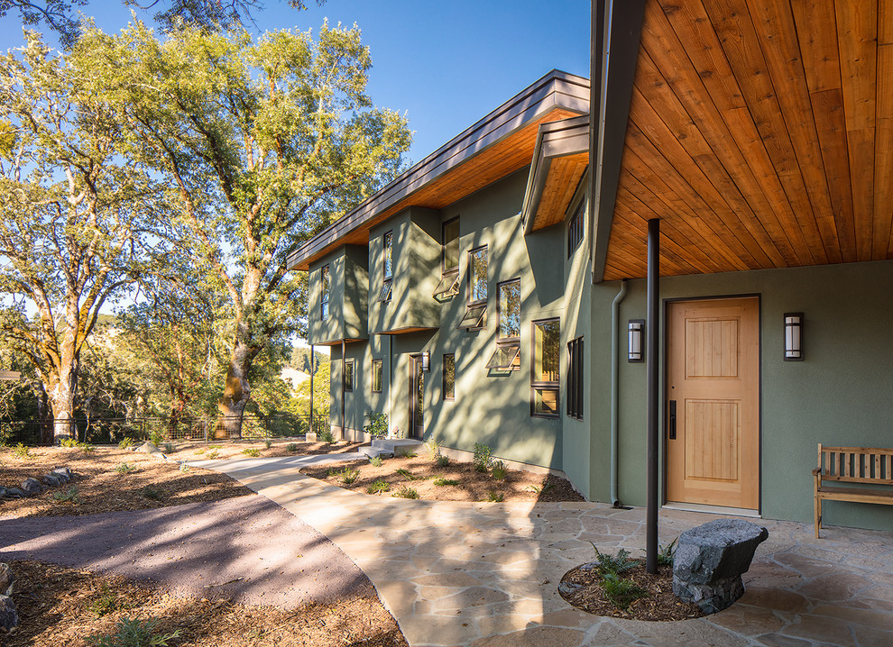 На фото: двухэтажный, зеленый частный загородный дом среднего размера в современном стиле с облицовкой из цементной штукатурки, плоской крышей и крышей из смешанных материалов