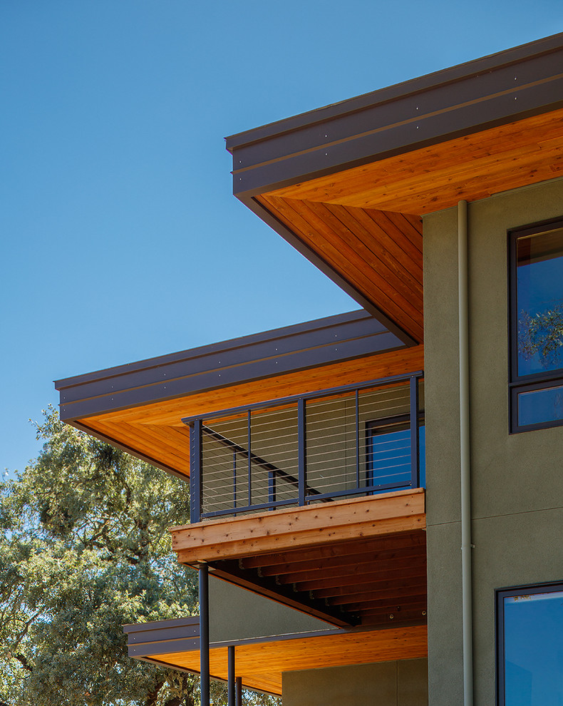 Cette photo montre une façade de maison verte tendance en stuc de taille moyenne et à un étage avec un toit plat et un toit mixte.