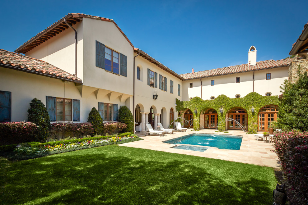 Example of a large tuscan beige two-story stucco exterior home design in Houston with a tile roof