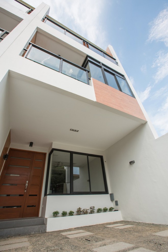 Foto della facciata di una casa a schiera bianca moderna a tre piani di medie dimensioni con copertura in metallo o lamiera