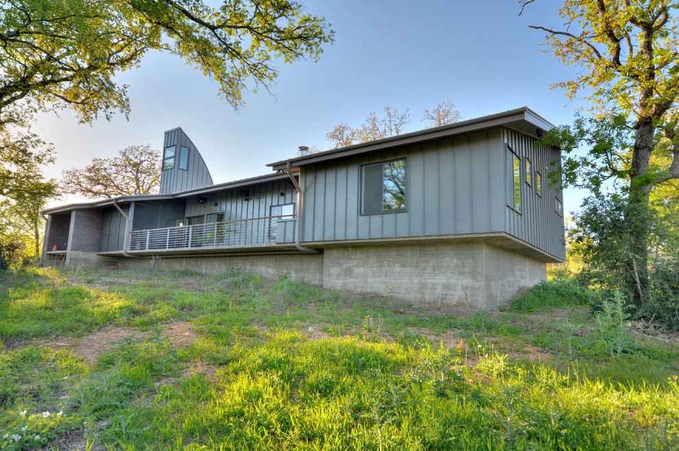 Photo of a medium sized and gey modern bungalow house exterior in Austin with metal cladding.
