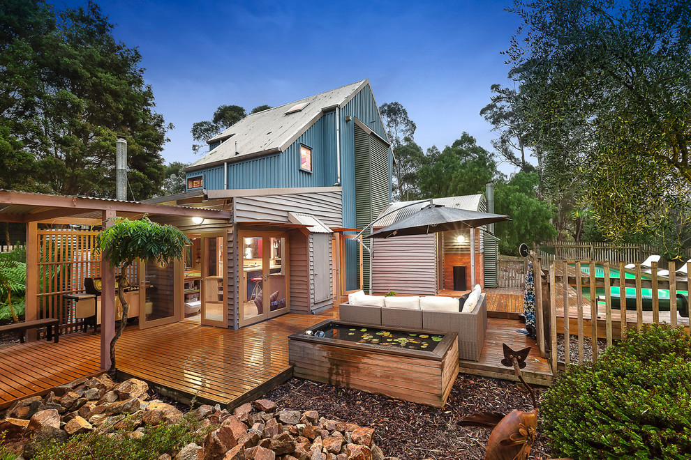 This is an example of a blue nautical house exterior in Melbourne with three floors, wood cladding and a pitched roof.