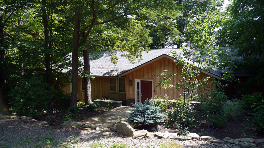 Cette image montre une façade de maison marron rustique en bois de taille moyenne et de plain-pied avec un toit à deux pans et un toit en shingle.