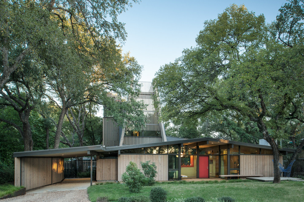 This is an example of a midcentury bungalow house exterior in Austin with wood cladding and a pitched roof.