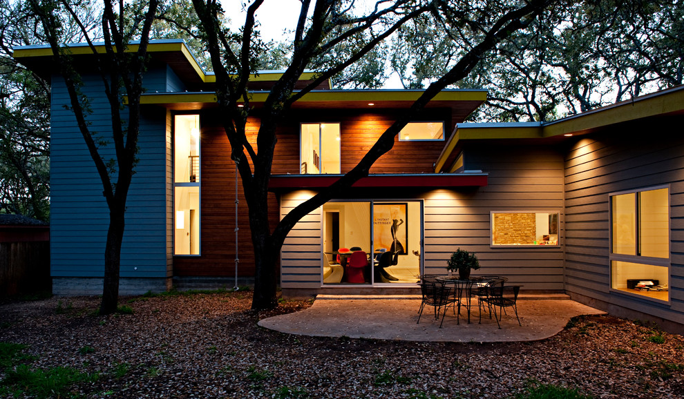 Example of a large mid-century modern gray two-story vinyl flat roof design in Austin