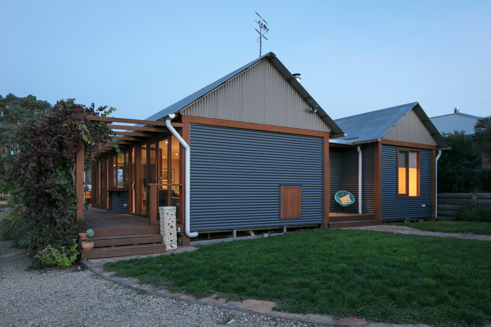 Foto på ett mellanstort eklektiskt hus, med allt i ett plan, sadeltak och tak i metall