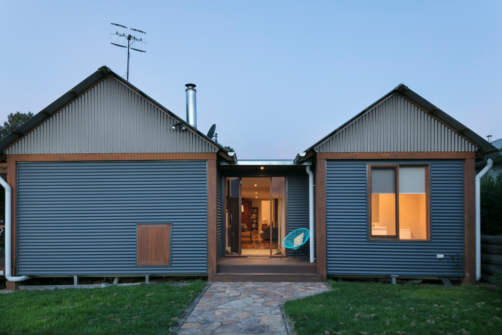 Imagen de fachada de casa ecléctica de tamaño medio de una planta con revestimiento de metal, tejado a dos aguas y tejado de metal