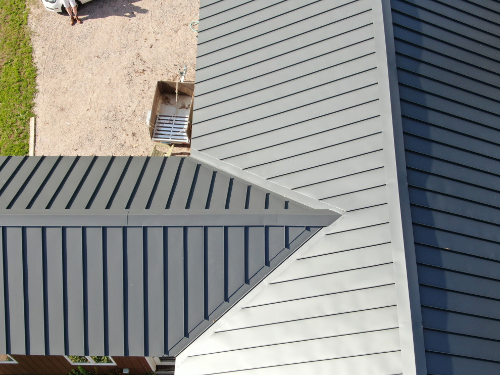 Exemple d'une façade de maison marron bord de mer en bois et planches et couvre-joints de taille moyenne et à un étage avec un toit à deux pans, un toit en métal et un toit gris.