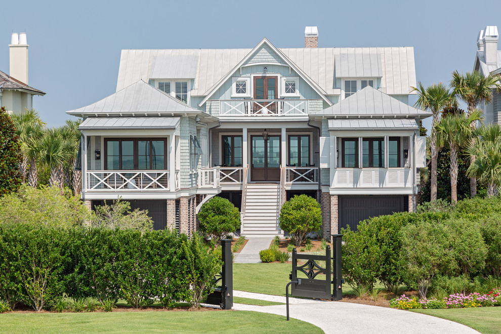 This is an example of a blue beach style detached house in Charleston with three floors, mixed cladding and a metal roof.