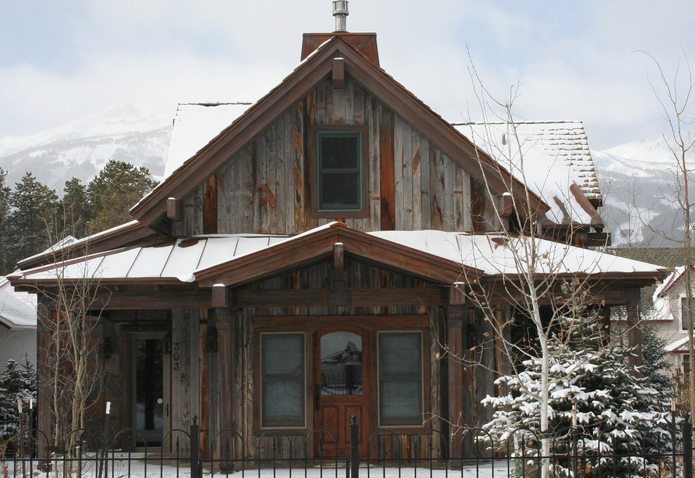 Exemple d'une façade de maison grise montagne en bois de taille moyenne et à un étage avec un toit à quatre pans.