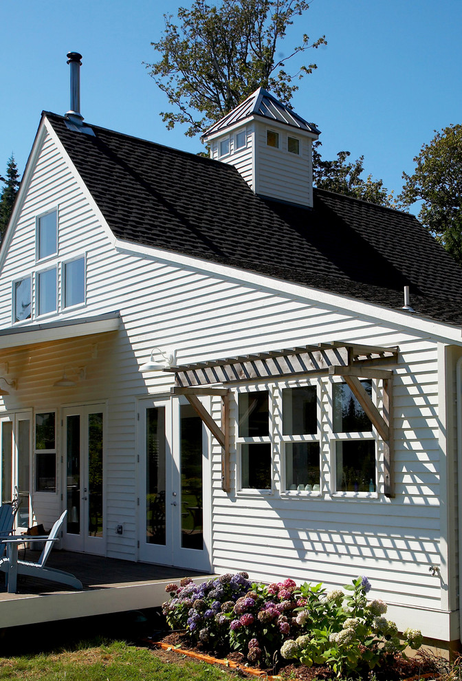 Example of a mid-sized transitional white two-story wood gable roof design in Seattle with a mixed material roof