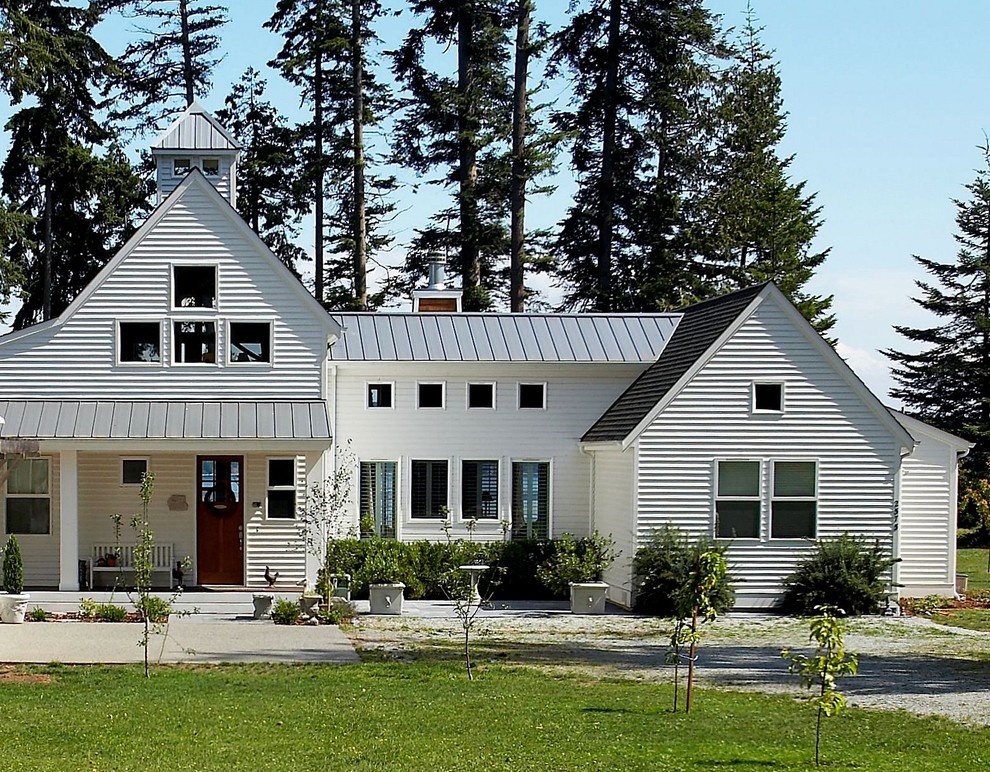 Aménagement d'une façade de maison blanche classique en bois à un étage et de taille moyenne avec un toit à deux pans et un toit en métal.