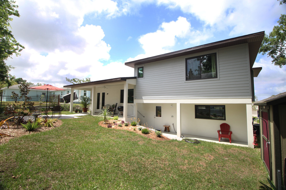 Mittelgroßes Retro Einfamilienhaus mit Mix-Fassade, grauer Fassadenfarbe, Satteldach und Schindeldach in Orlando