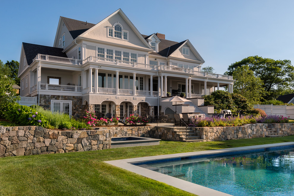 Cette photo montre une façade de maison beige bord de mer à deux étages et plus avec un revêtement mixte et un toit à deux pans.