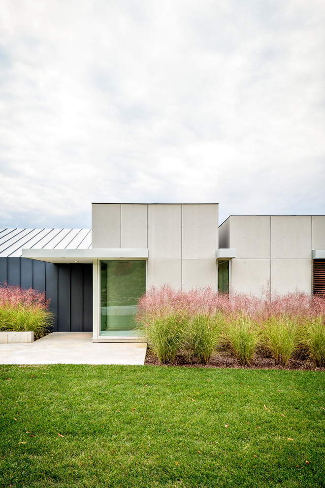 Réalisation d'une façade de maison grise minimaliste en panneau de béton fibré de plain-pied.