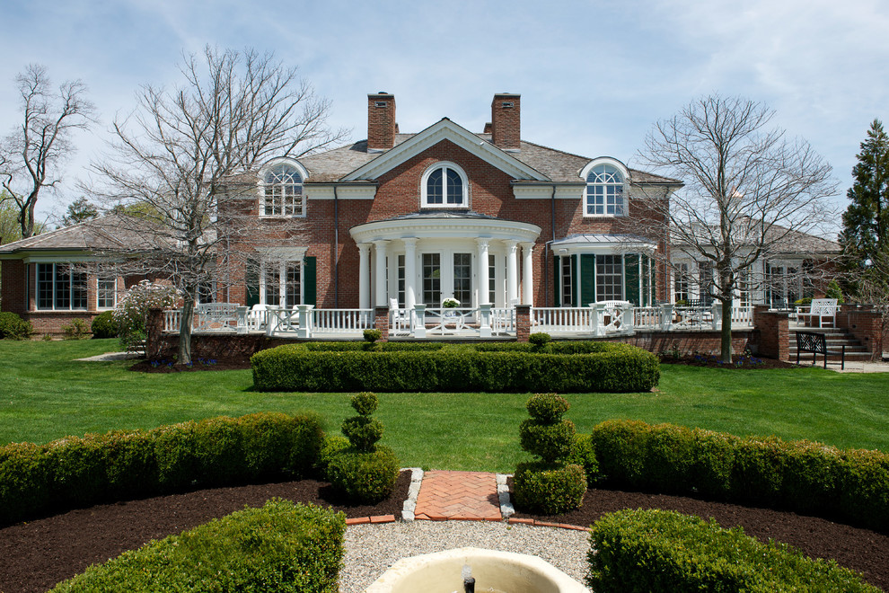Inspiration for a large red two-story brick exterior home remodel in New York with a hip roof