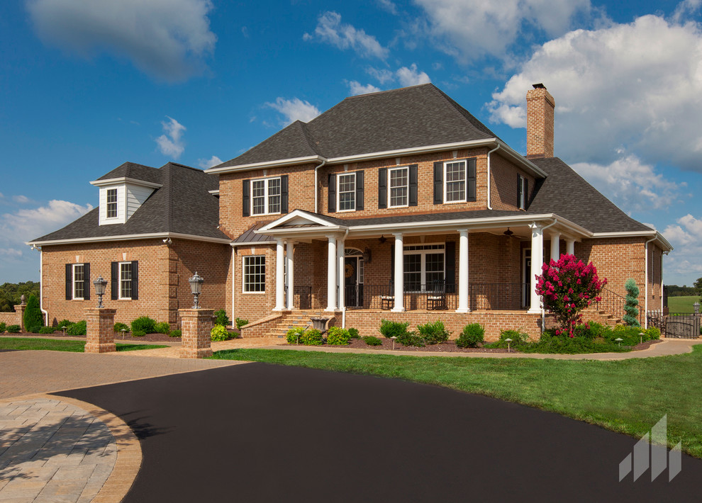 Large elegant brown two-story brick exterior home photo in Other with a clipped gable roof