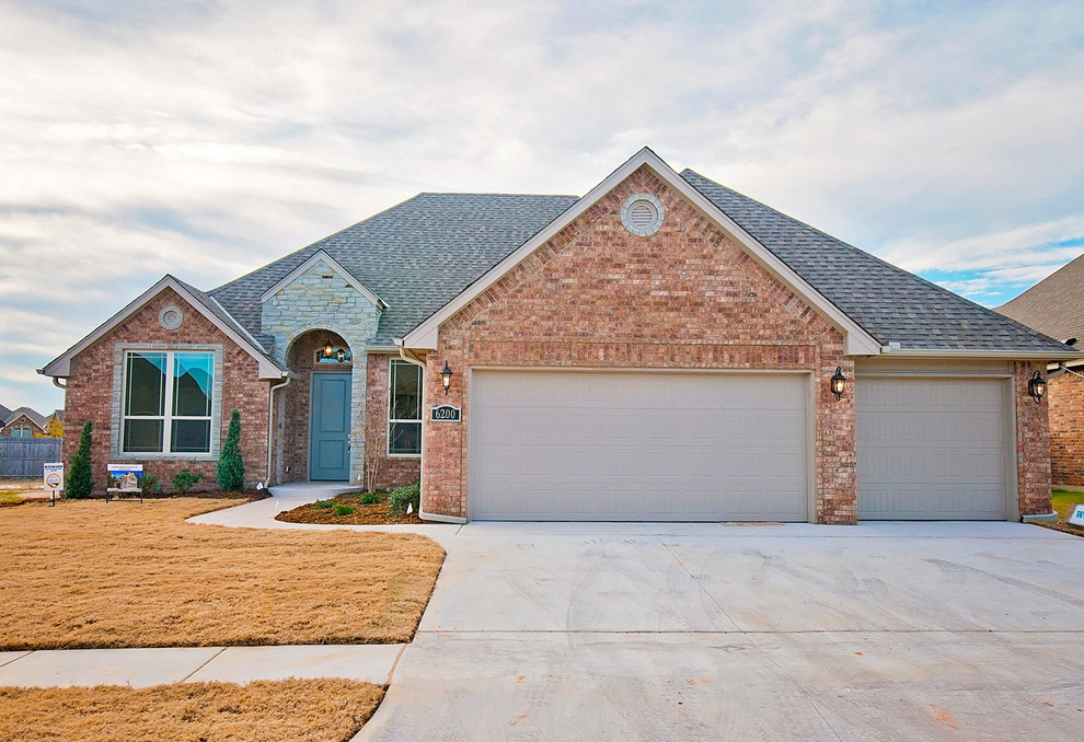 This is an example of a large and beige classic bungalow brick house exterior in Oklahoma City with a pitched roof.