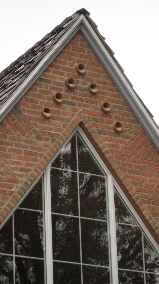 Cette photo montre une grande façade de maison marron chic en brique à un étage avec un toit à deux pans.