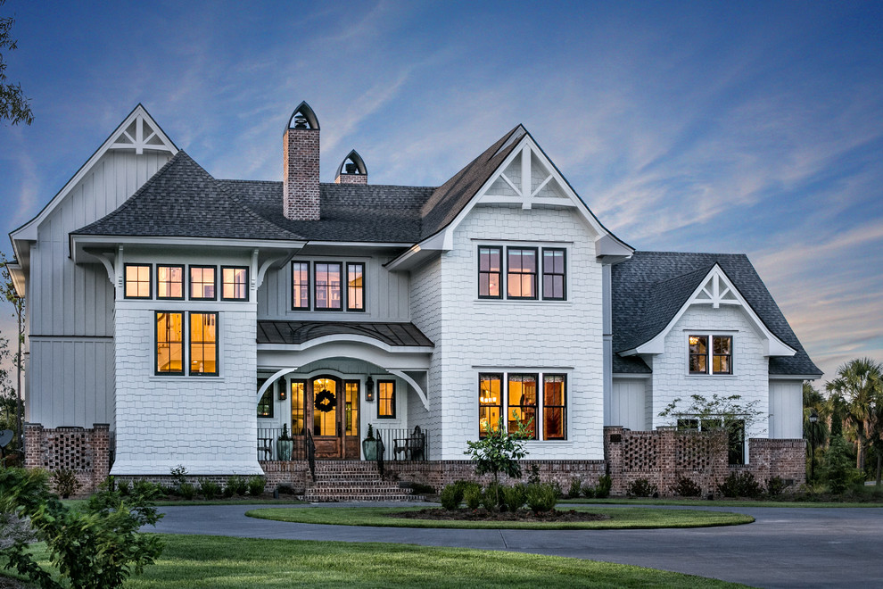 Cette image montre une grande façade de maison blanche traditionnelle en bois à un étage avec un toit mixte.