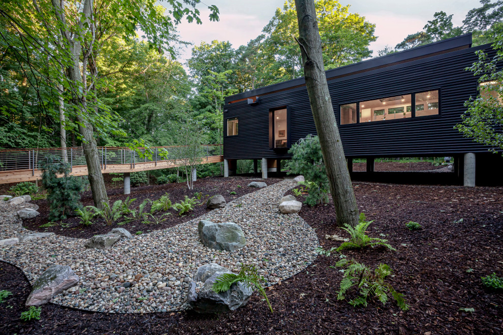 На фото: одноэтажный, черный частный загородный дом среднего размера в стиле ретро с облицовкой из металла, плоской крышей и зеленой крышей с