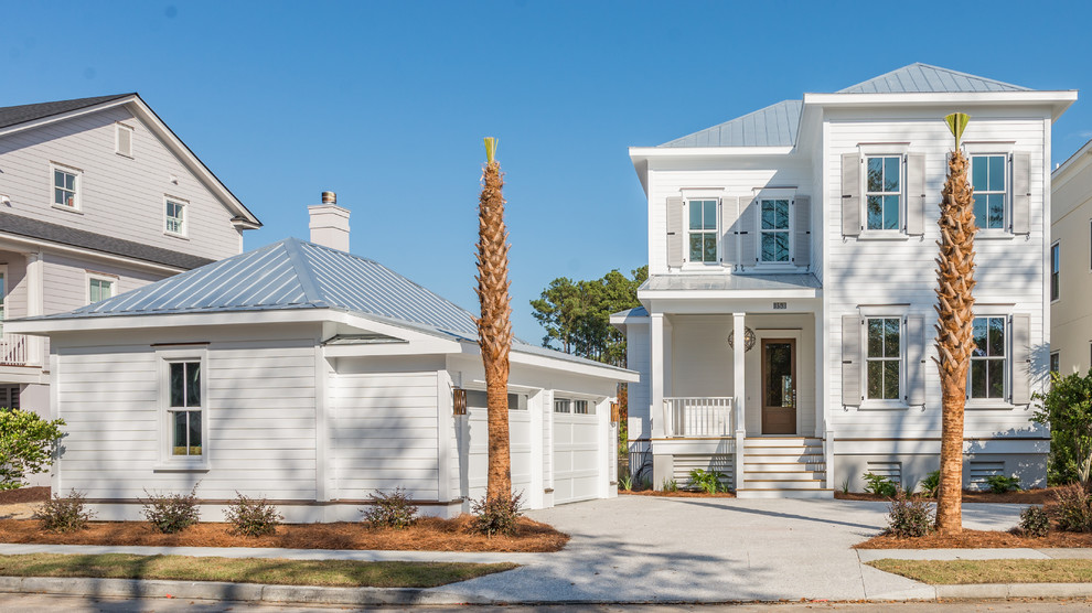 White and large beach style two floor detached house in Charleston with a hip roof, a metal roof and vinyl cladding.