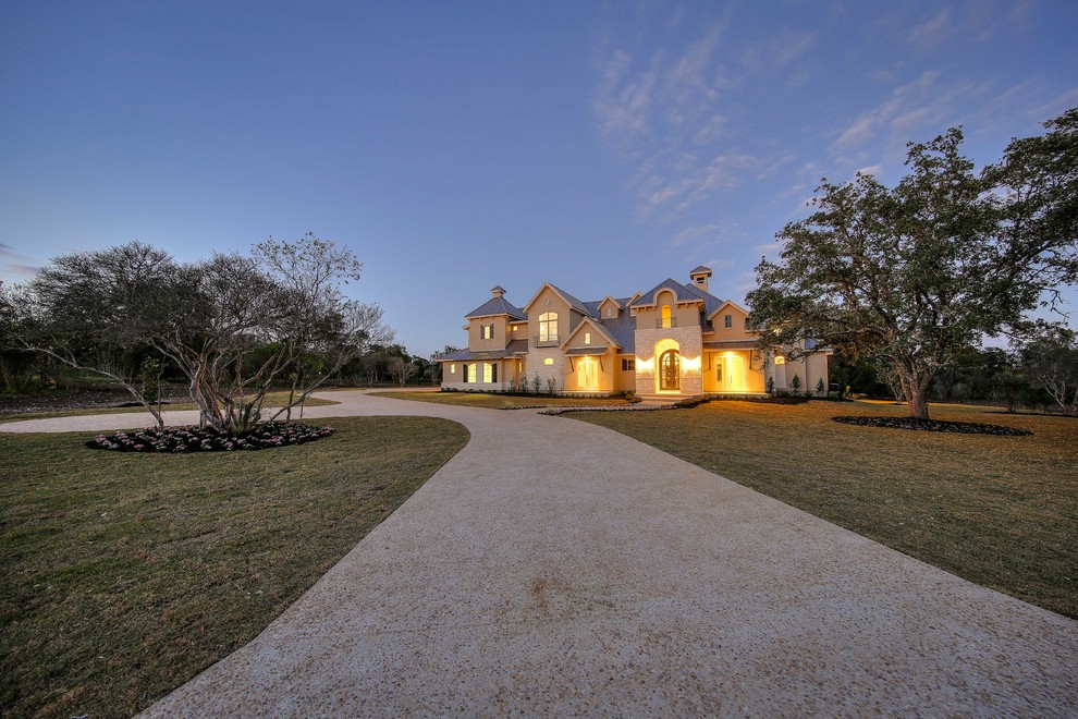 This is an example of a large and beige traditional two floor render house exterior in Austin.