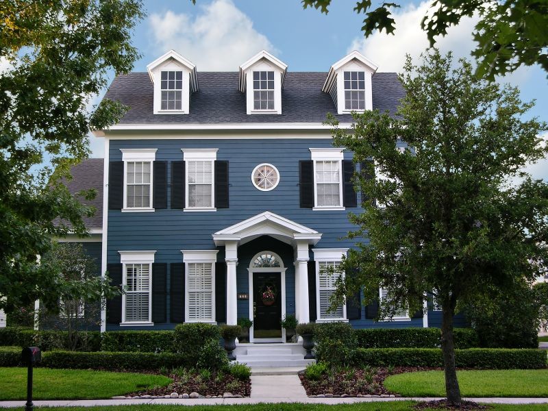 Пример оригинального дизайна: большой, трехэтажный, синий частный загородный дом в классическом стиле с крышей из гибкой черепицы и облицовкой из винила