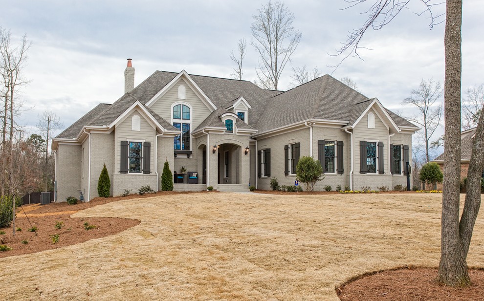 This is an example of a large and beige classic two floor house exterior in Other with stone cladding and a hip roof.
