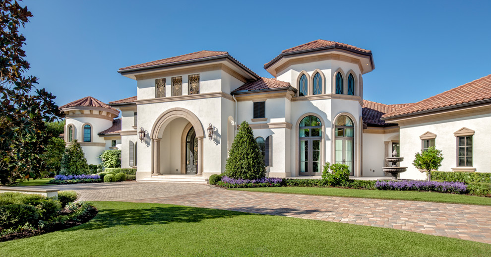 Large tuscan beige one-story stucco house exterior photo in Miami with a hip roof and a tile roof